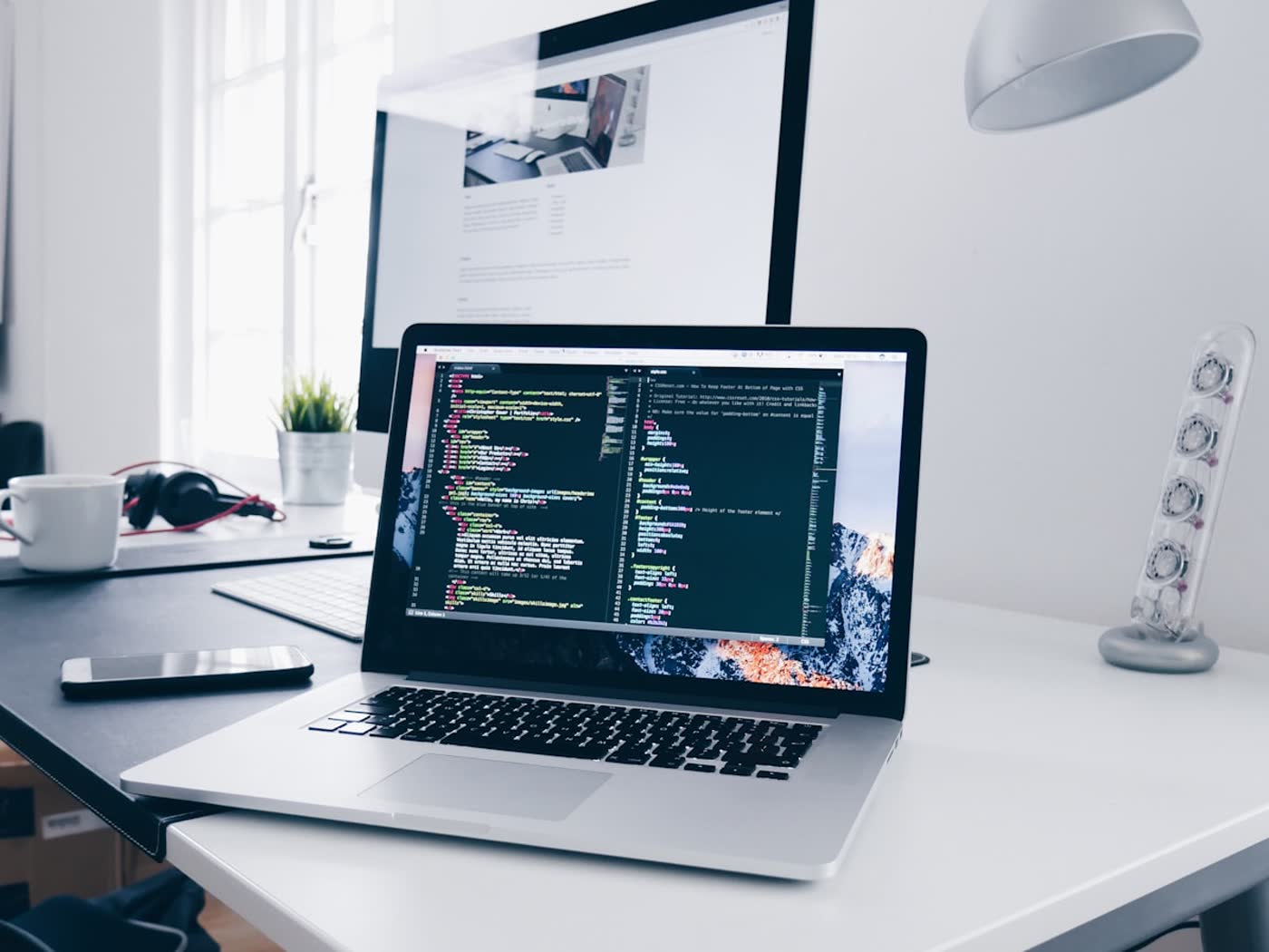Clean modern desk with a laptop, coffee mug and headphones in soft natural light